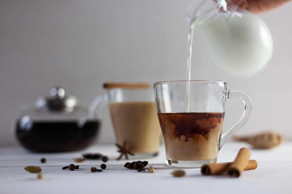 Homemade chai latte being prepared with tea, spices, and milk in a pot